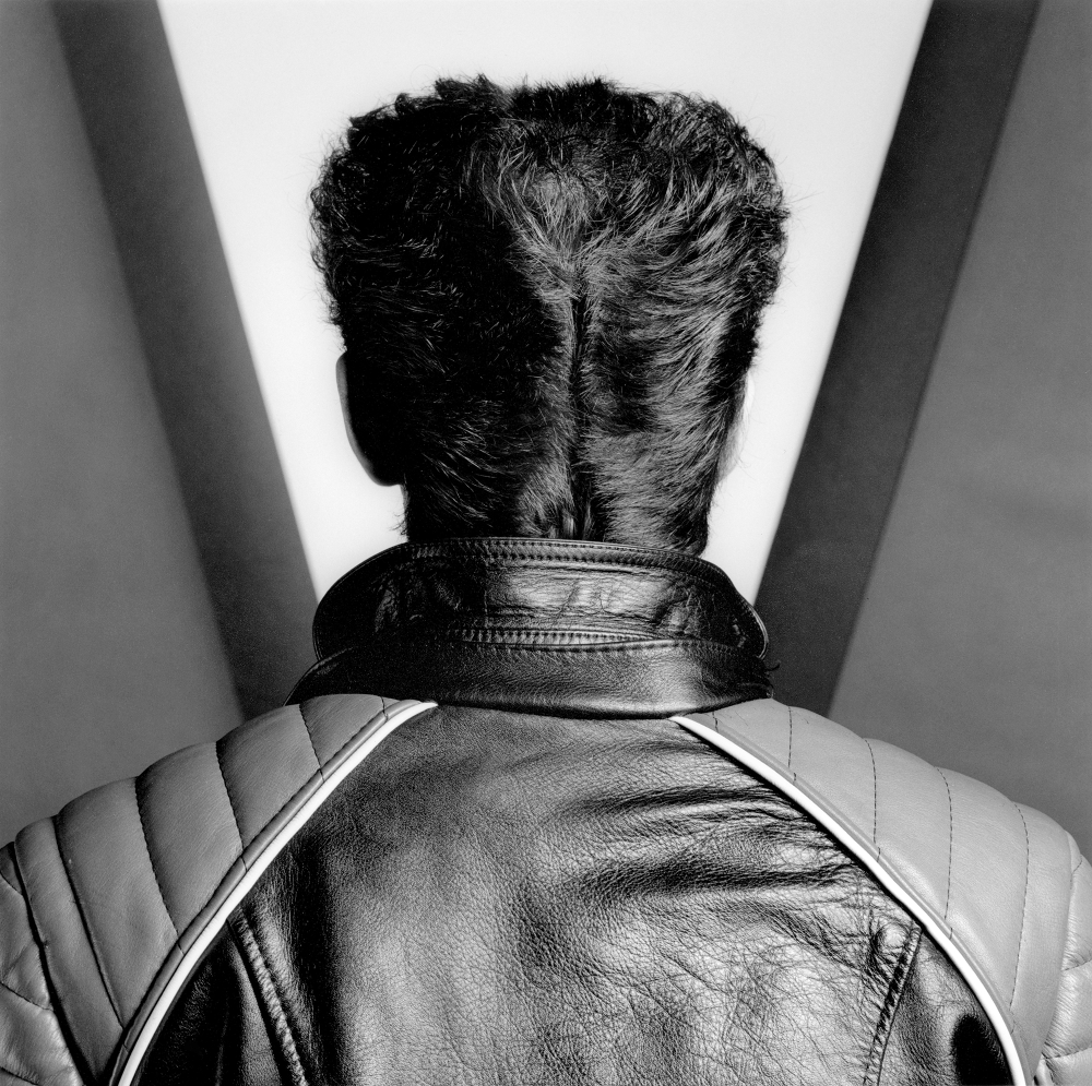 Self portrait of Mapplethorpe wearing a leather jacket facing away from the camera.