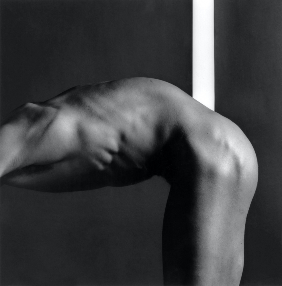 Nude black man bending forward with head out of frame.