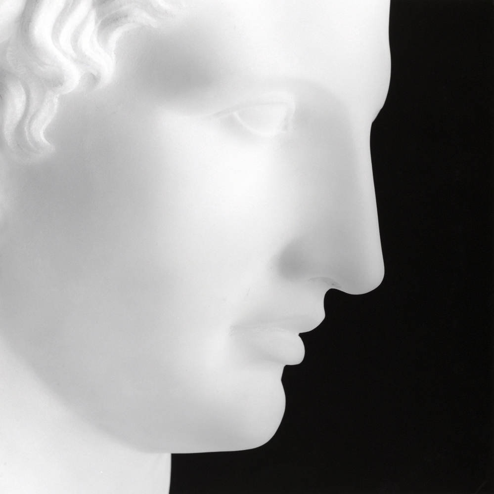 Sculpture of Hermes showing the figure's face in profile set against a black background
