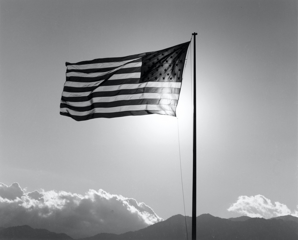 Backlit, backwards American flag waving in the breeze.
