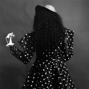 Portrait of a woman in a polka dot dress and hat from behind.