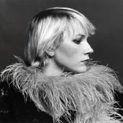 Close-up of a woman in profile wearing a diamond earring and a feather boa.