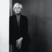 Andy Warhol leaning against a wall.