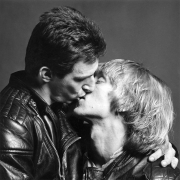 Two white men in leather jackets kissing.