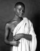 Nude black woman holding up a cloth.