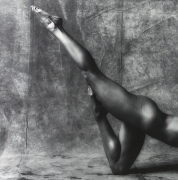 Side view of a muscular woman from the waist down posing with one knee bent on the ground and the other leg extended upward diagonally behind her.