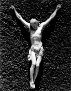 A white crucifix attached to a textured black stone surface.