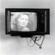 Television with woman on the screen, with lock and chain hanging off.