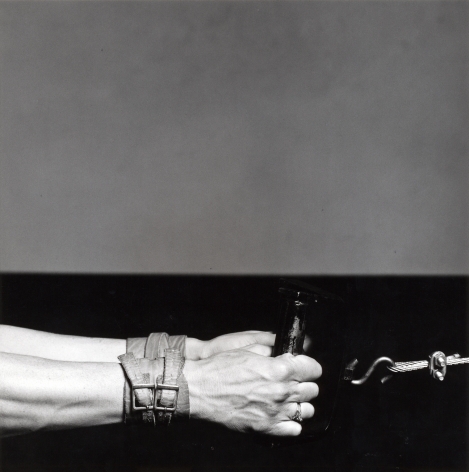 Lisa Lyon's hands grabbing at weight, with leather buckle bracelets.