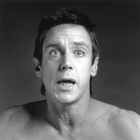 Shirtless Iggy Pop from the chest up, mouth open and eyes wide.