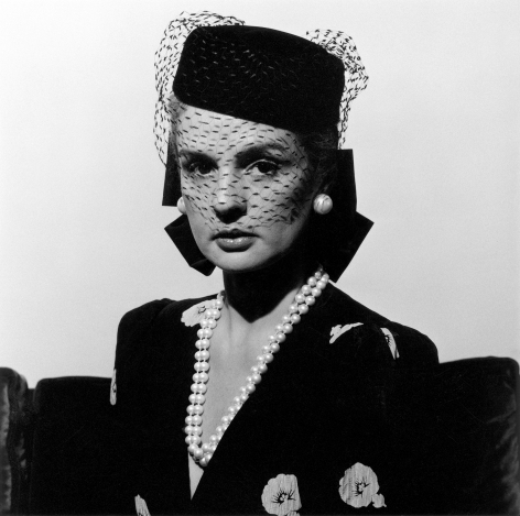 Close-up of fashion designer Carolina Herrera wearing a birdcage hat and pearl jewelry.