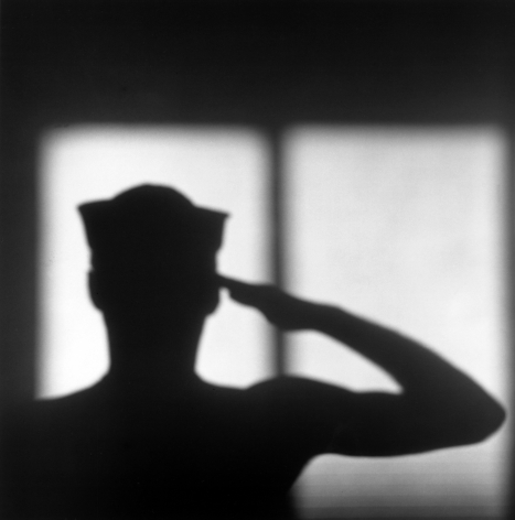 Jack Walls' shadow against wall, wearing hat and saluting.