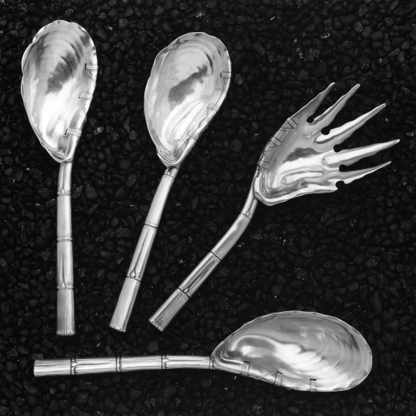 Four pieces of silverware against a dark pebbled background.